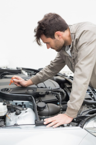 Man using dipstick to check oil in his car