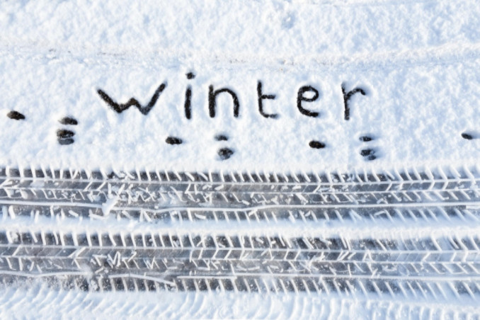 Snow on road with tracks and the word winter written in it